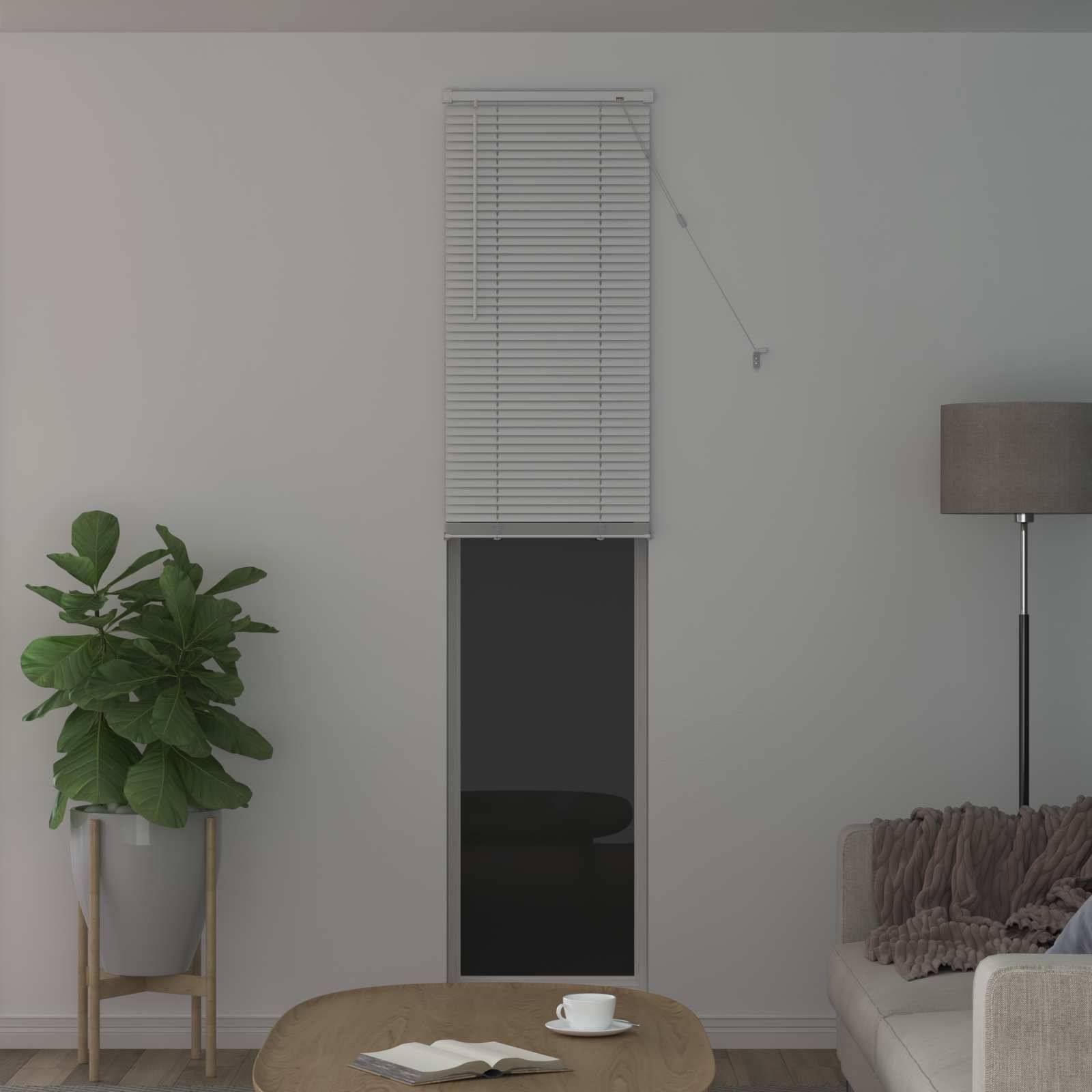 Ein gemütliches Wohnzimmer verfügt über ein kleines Fenster mit geschlossenen Jalousien, eine hohe Pflanze, eine Stehleuchte und ein Sofa mit einer Wurfdecke.