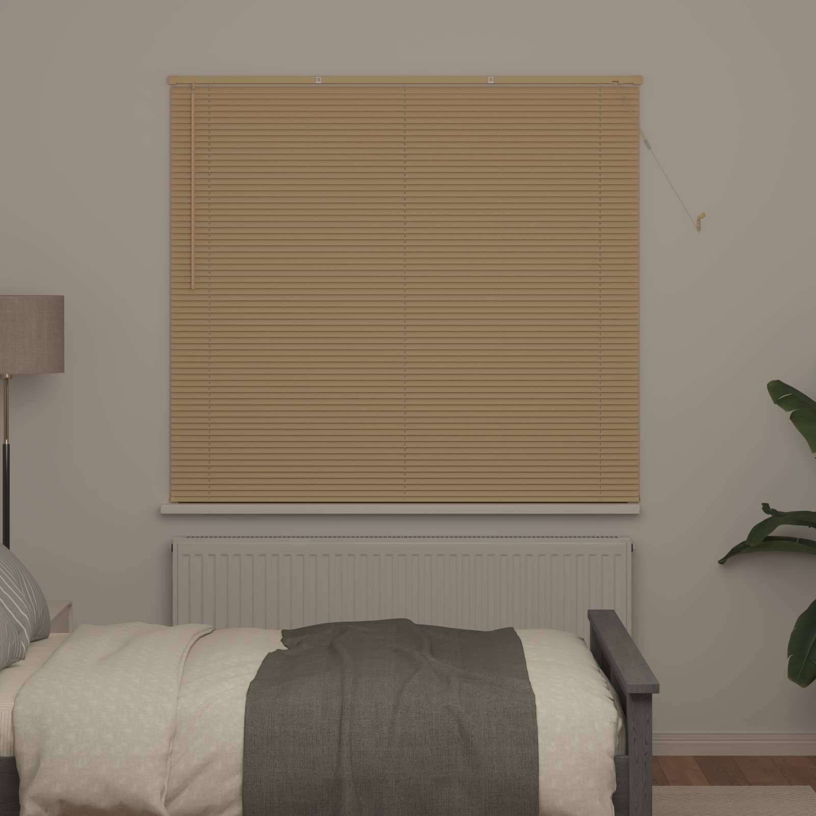 Ein ordentlich gemachtes Bett mit einer grauen Decke blickt auf ein Fenster mit geschlossenen beigen Jalousien in einem minimalistischen Schlafzimmer. Eine Pflanze und eine Lampe sind sichtbar.