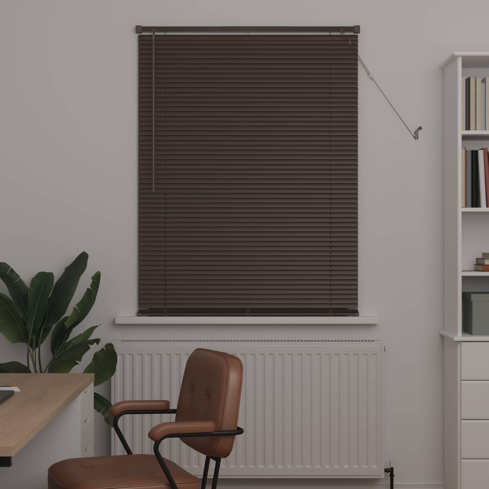 Eine moderne Büroecke mit einem braunen, mit Jalousien bedeckten Fenster, einem Schreibtisch, einem braunen Stuhl, einer Pflanze und einem weißen Bücherregal mit Büchern und Dekorationselementen.