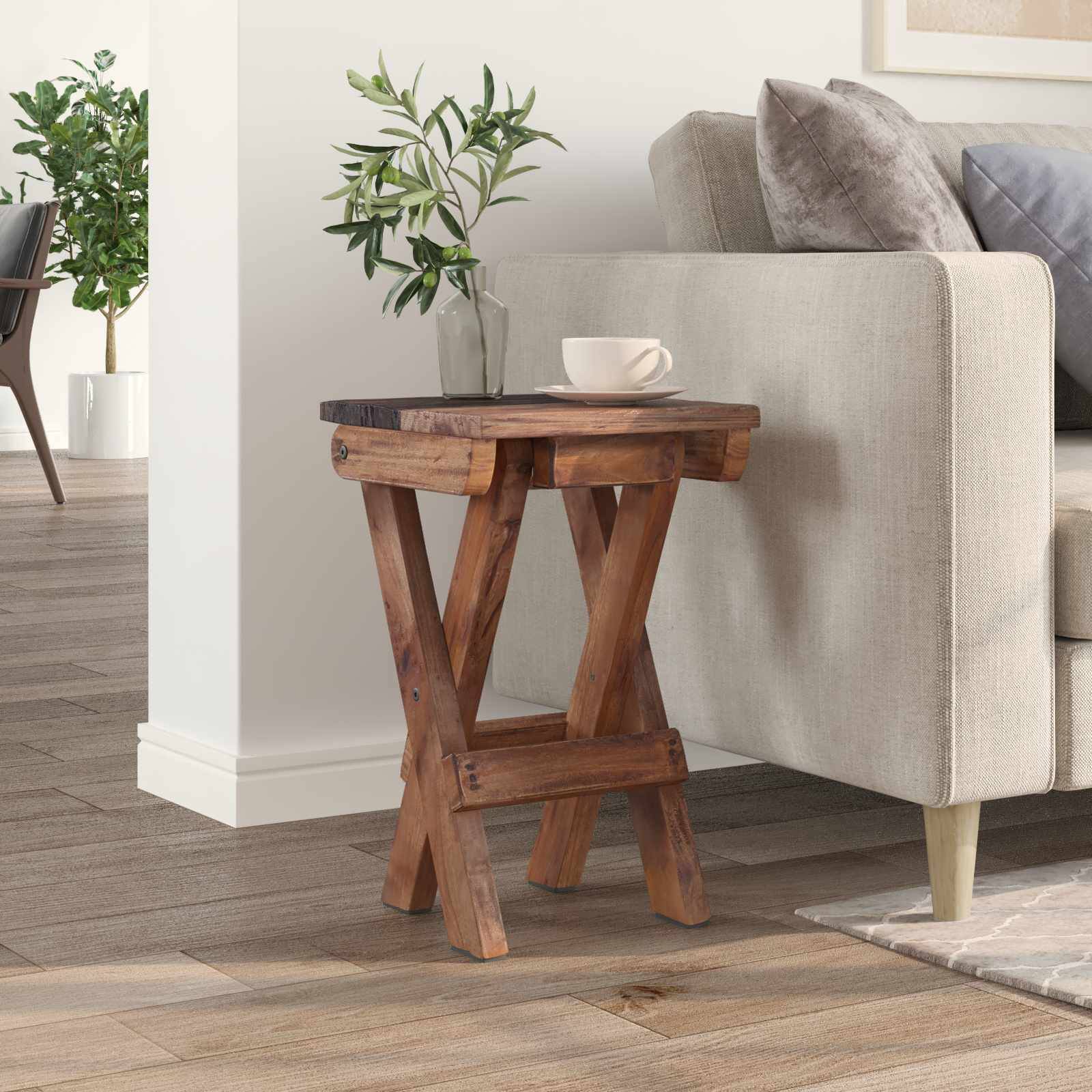 Eine gemütliche Ecke des Wohnzimmers mit einem Holzbeistelltisch, auf dem eine weiße Tasse steht, neben einem beigefarbenen Sofa und einer Pflanze im Hintergrund.