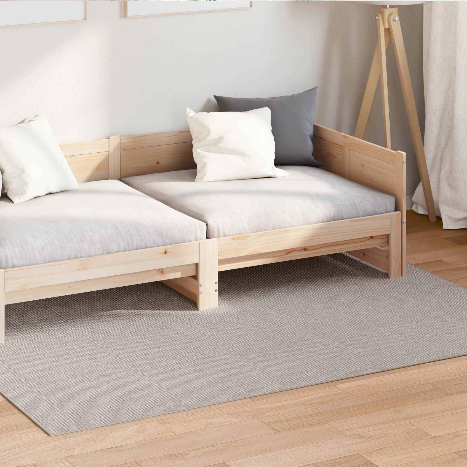 Kleines Holzecksofa auf einem beigen Teppich mit weißen und grauen Kissen, in einem minimalistischen Raum eingerichtet.