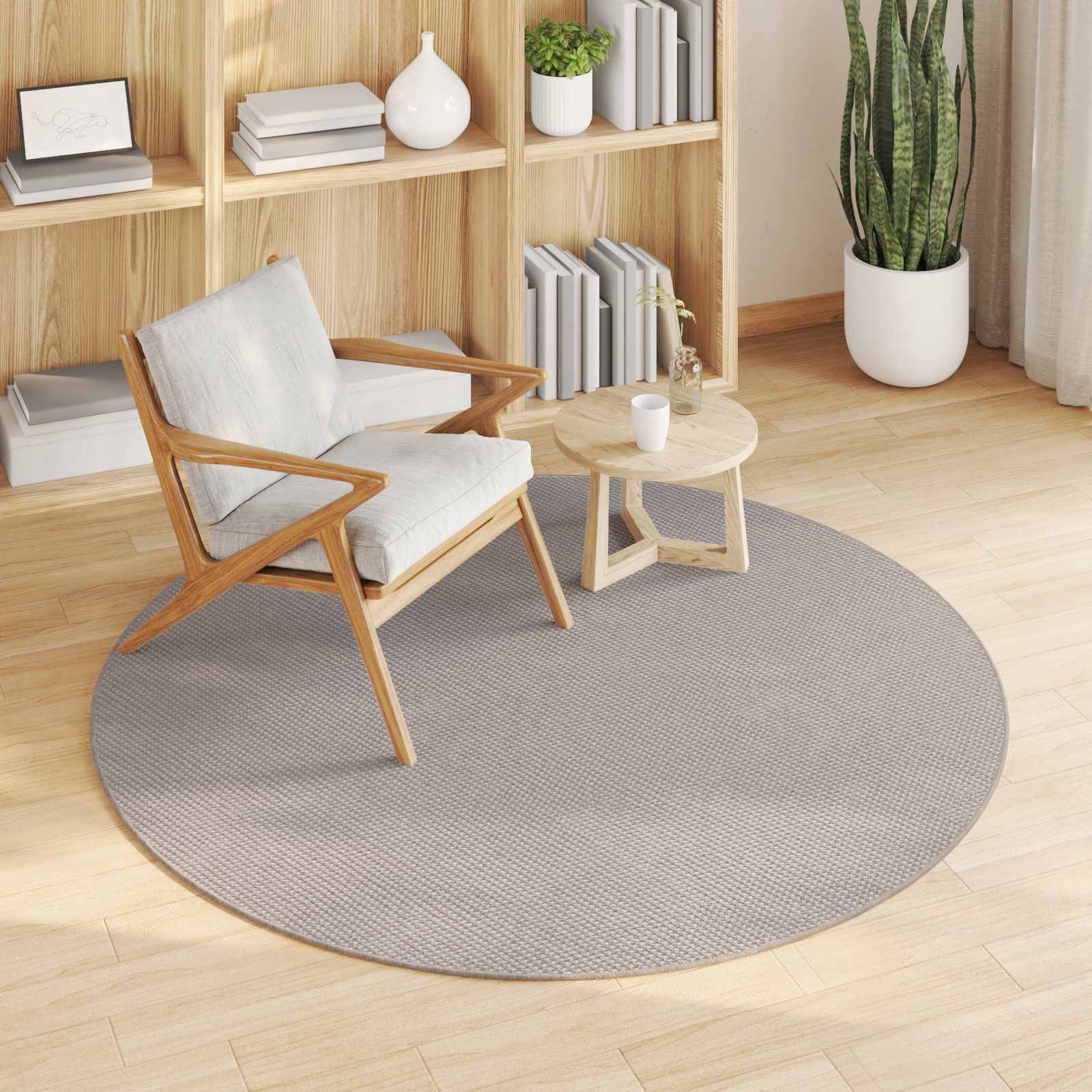 Ein minimalistischer Wohnraum mit einem Holzsessel, rundem Tisch, rundem Teppich, Bücherregalen mit Dekoration und Topfpflanzen.