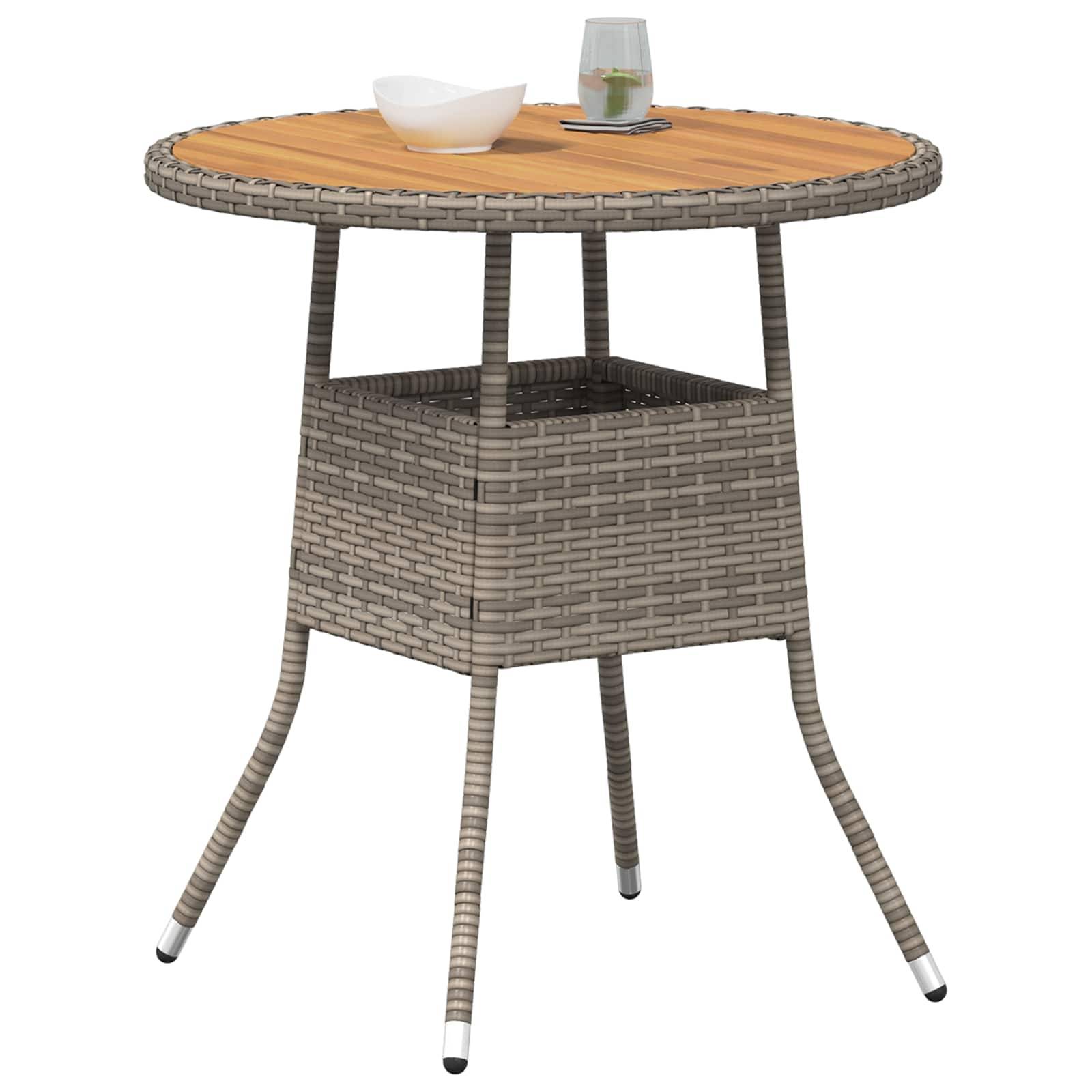 Ein runder Flechttiisch mit einer Holzplatte hält eine kleine Schale und ein Glas mit einem Getränk. Der Tisch hat vier schräge Beine und ein unteres Regal.