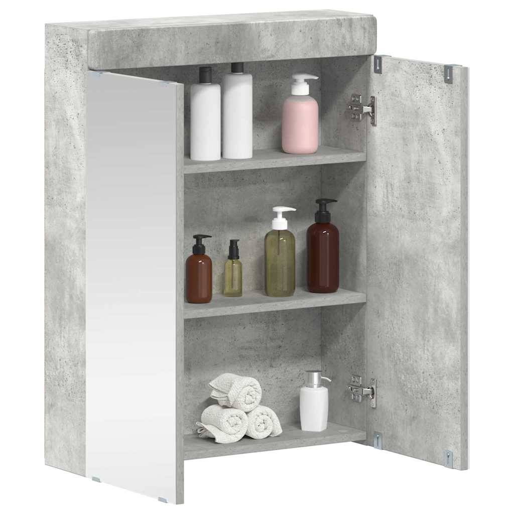 Ein Badezimmerschrank mit Betonoptik und einem Spiegel auf einer Tür, der verschiedene Flaschen, Handtücher und Toilettenartikel auf drei Regalen enthält.