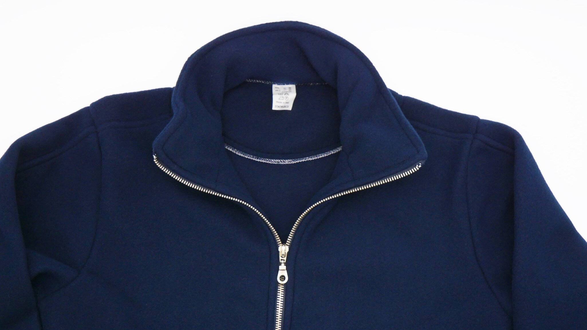 Eine dunkelblau Jacke mit einem Reißverschluss wird gezeigt, die einen hohen Kragen und ein Sweatshirt darunter aufweist. Der Reißverschluss ist teilweise geöffnet.