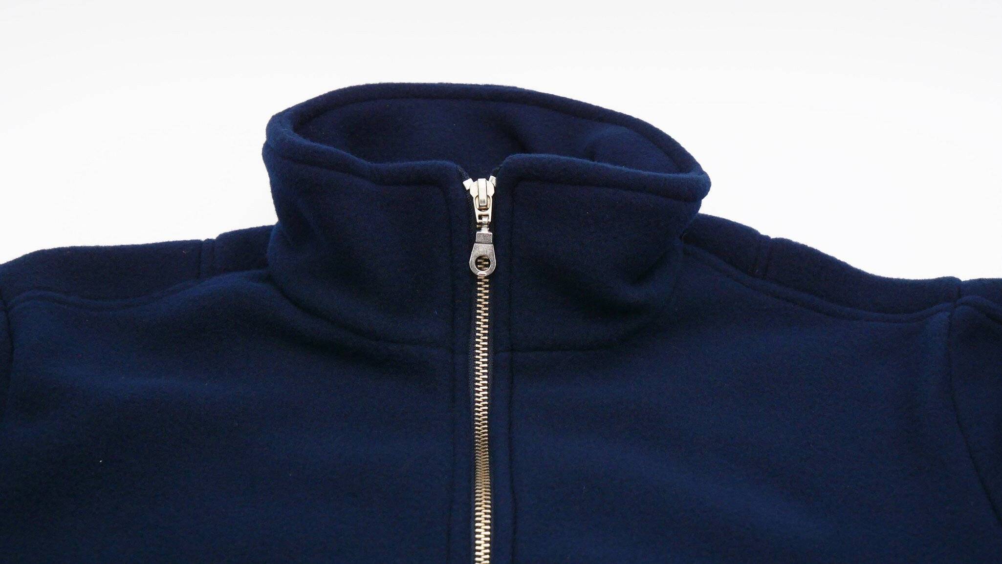 Eine dunkelblau Fleecejacke mit hohem Kragen und einem silbernen Reißverschluss, der teilweise geöffnet ist.