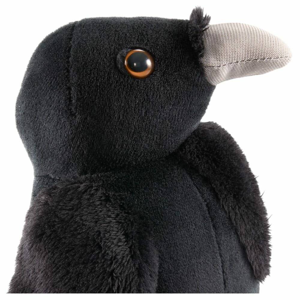 Ein weiches, schwarzes Vogel-Spielzeug mit prominentem Schnabel und Knopfaugen, nach rechts schauend.