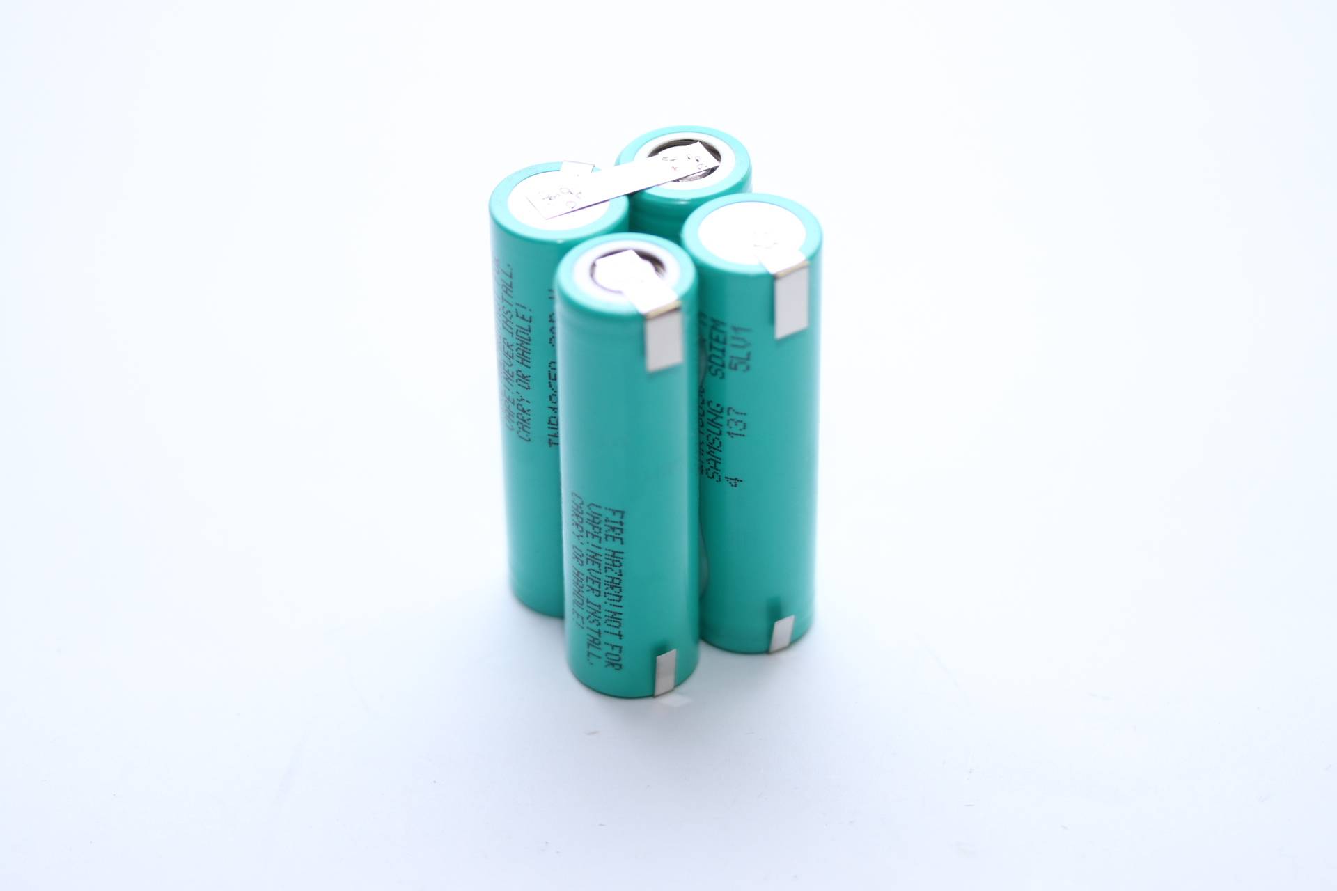 Vier türkisfarbene zylindrische Batterien in einem Set verbunden, mit Metallkontakten an der Oberseite, vor hellem Hintergrund.