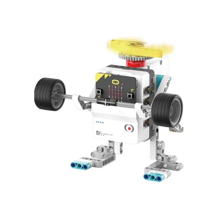Ein kleiner, fahrbarer Roboter aus farbenfrohen Spielzeugbausteinen, mit einem sich drehenden gelben Kreisel, zwei großen schwarzen Rädern und blau gespitzten Füßen.
