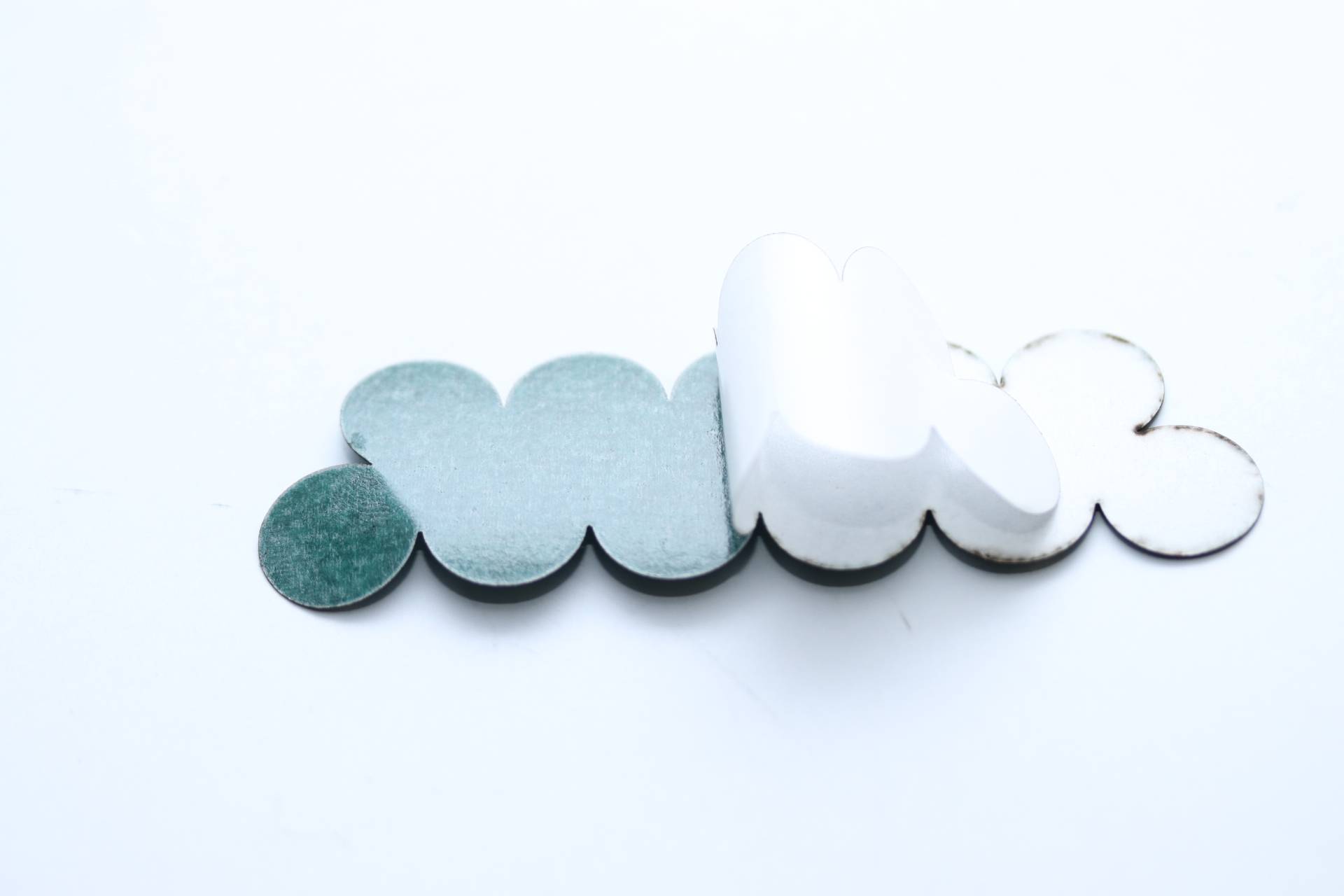 Das Bild zeigt dreidimensionale Wolkenformen aus weichem Material, die sich in Grün- und Weißtönen überlappen.