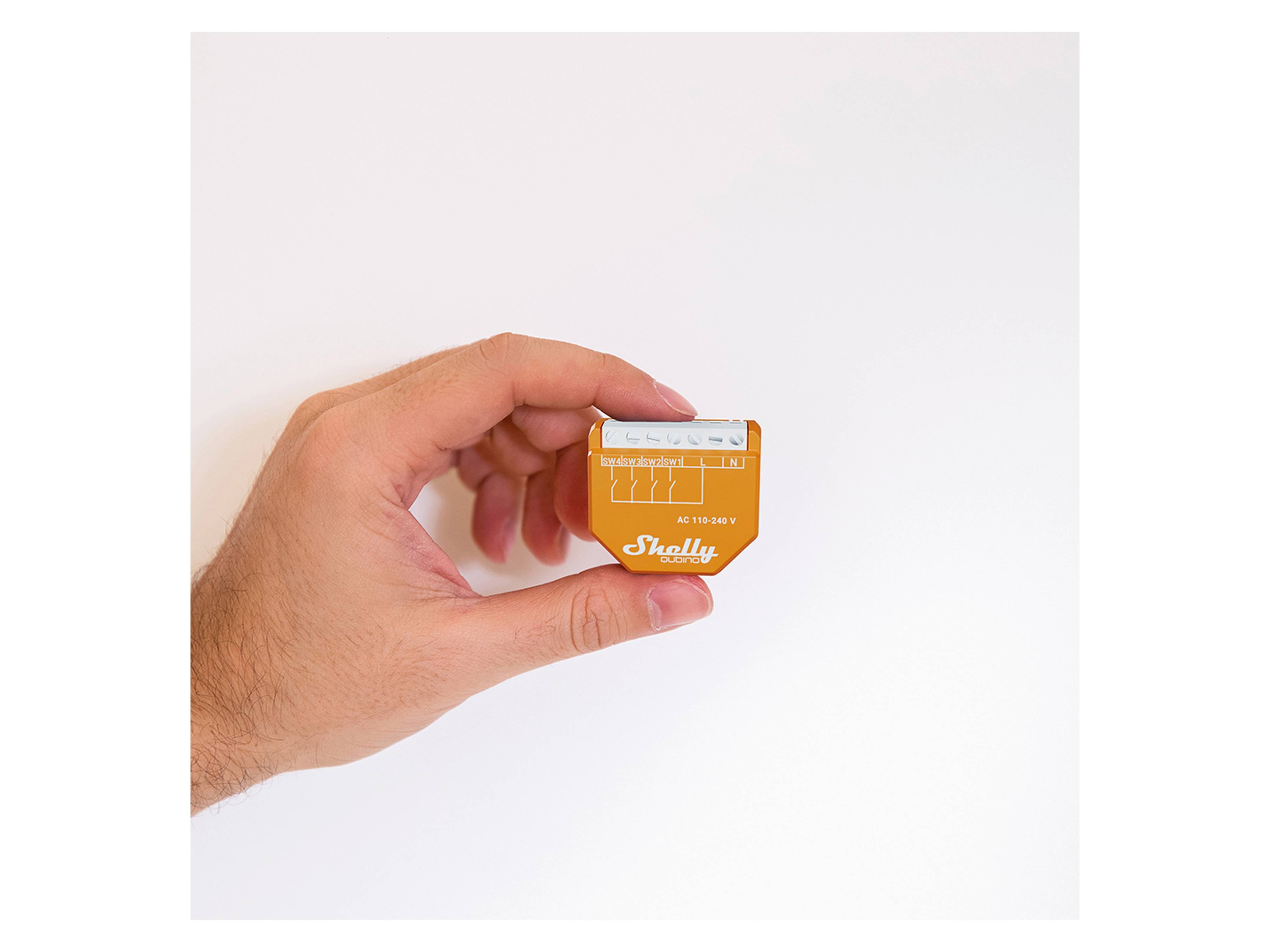 Eine Hand hält ein Shelly AC 110-230V Smart-Relay-Gerät vor einem weißen Hintergrund.