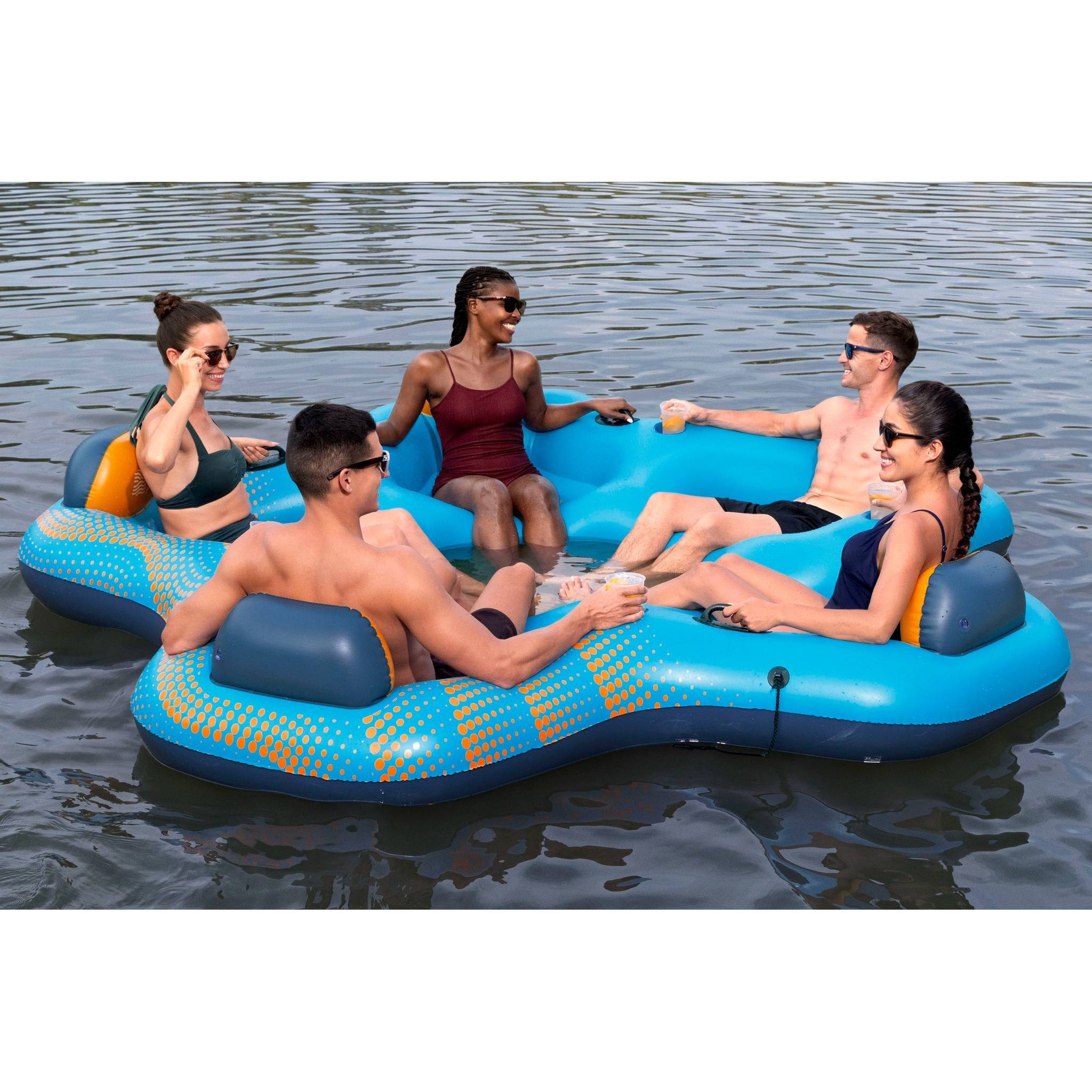 Zwei Hände montieren eine graue Kunststoffarmatur auf ein rundes blaues Objekt mit hervorstehenden Rohren, alles auf einer hellgrauen Oberfläche.