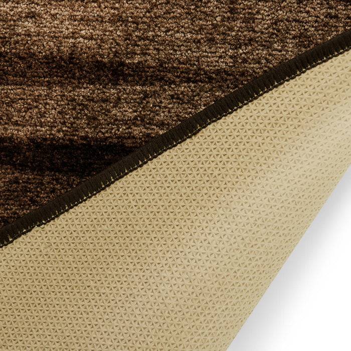 Eine Ecke eines braun strukturierten Teppichs wird umgeklappt und offenbart eine beige rutschfeste Rückseite mit einem dreieckigen Muster, was sichere Platzierung anzeigt.