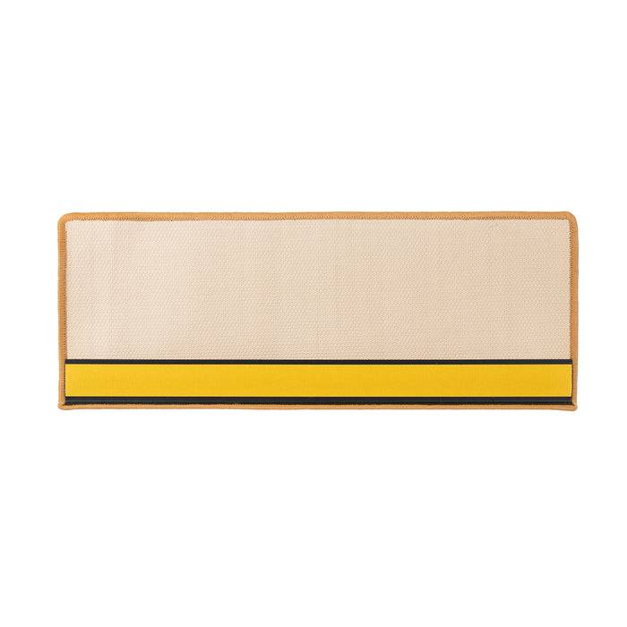 Eine rechteckige gewebte Matte mit einer beigefarbenen Oberfläche und einem kräftigen gelben Streifen am unteren Ende, begrenzt von dünnen schwarzen Linien.