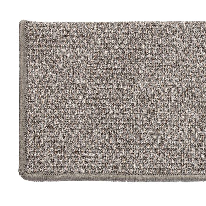 Ein rechteckiger beiger Fußabtreter mit strukturierter Oberfläche und gesteppten Kanten.