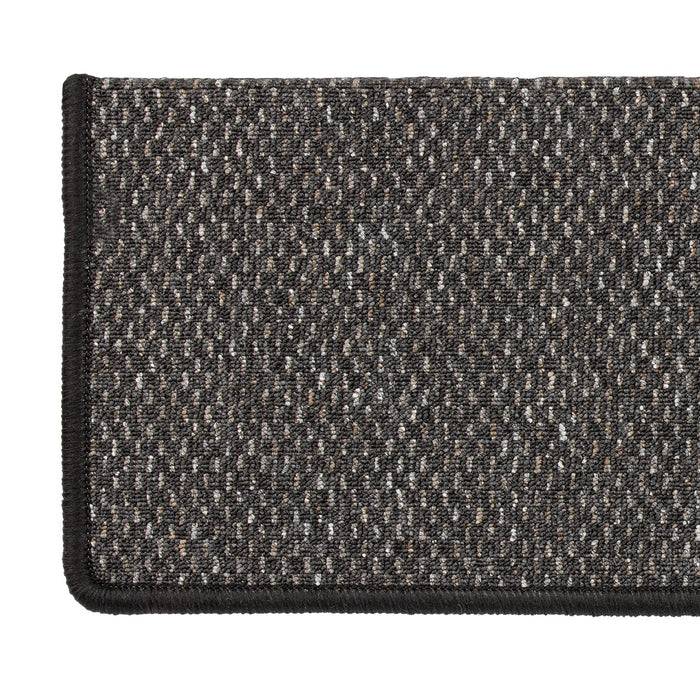 Ein Nahaufnahmebild eines strukturierten, dunkelgrauen rechteckigen Teppichs mit einem gewebten Muster und schwarzem Rand, das die Details des Stoffes und der Webung zeigt.