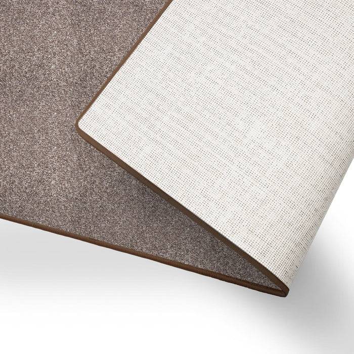 Ein gefalteter, zweifarbiger Teppich mit einer grauen strukturierten Oberfläche und einer glatten weißen Unterseite, der sein reversibles Design zeigt.