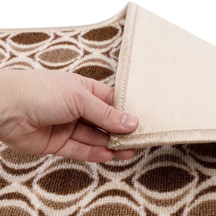 Eine Hand hebt die Ecke eines beige und braun gemusterten Teppichs an und zeigt dessen Textur und Rückseite.