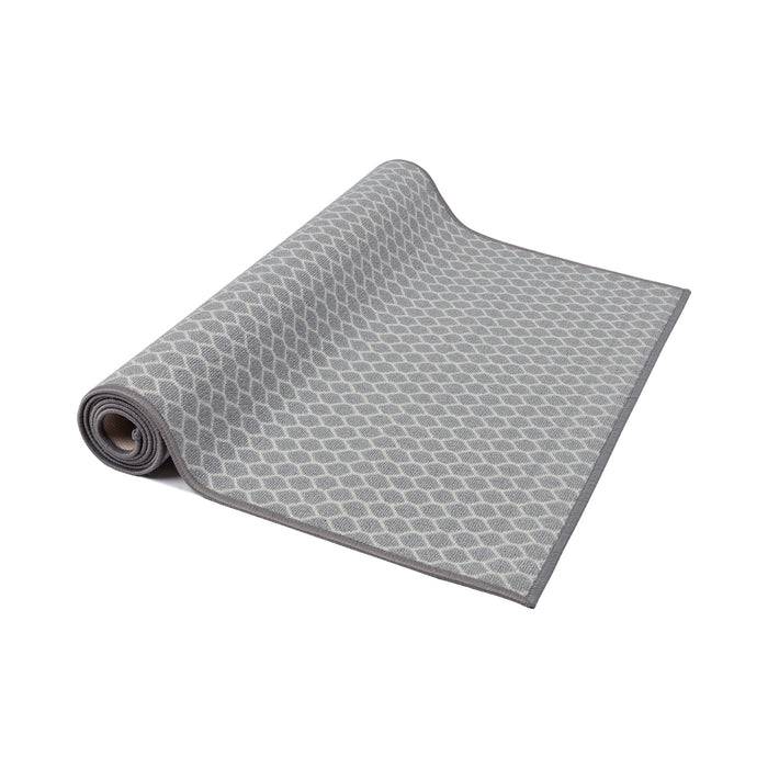 Ein grauer aufgerollter Teppich mit einem Rautenmusterdesign, auf weißem Hintergrund präsentiert.