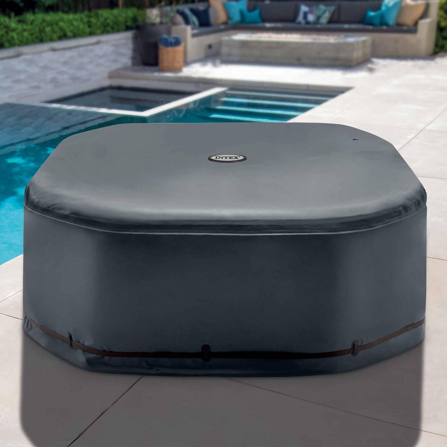 Runder, abgedeckter, grauer aufblasbarer Whirlpool auf einer Terrasse neben einem Pool, mit Außensitzgelegenheiten im Hintergrund.