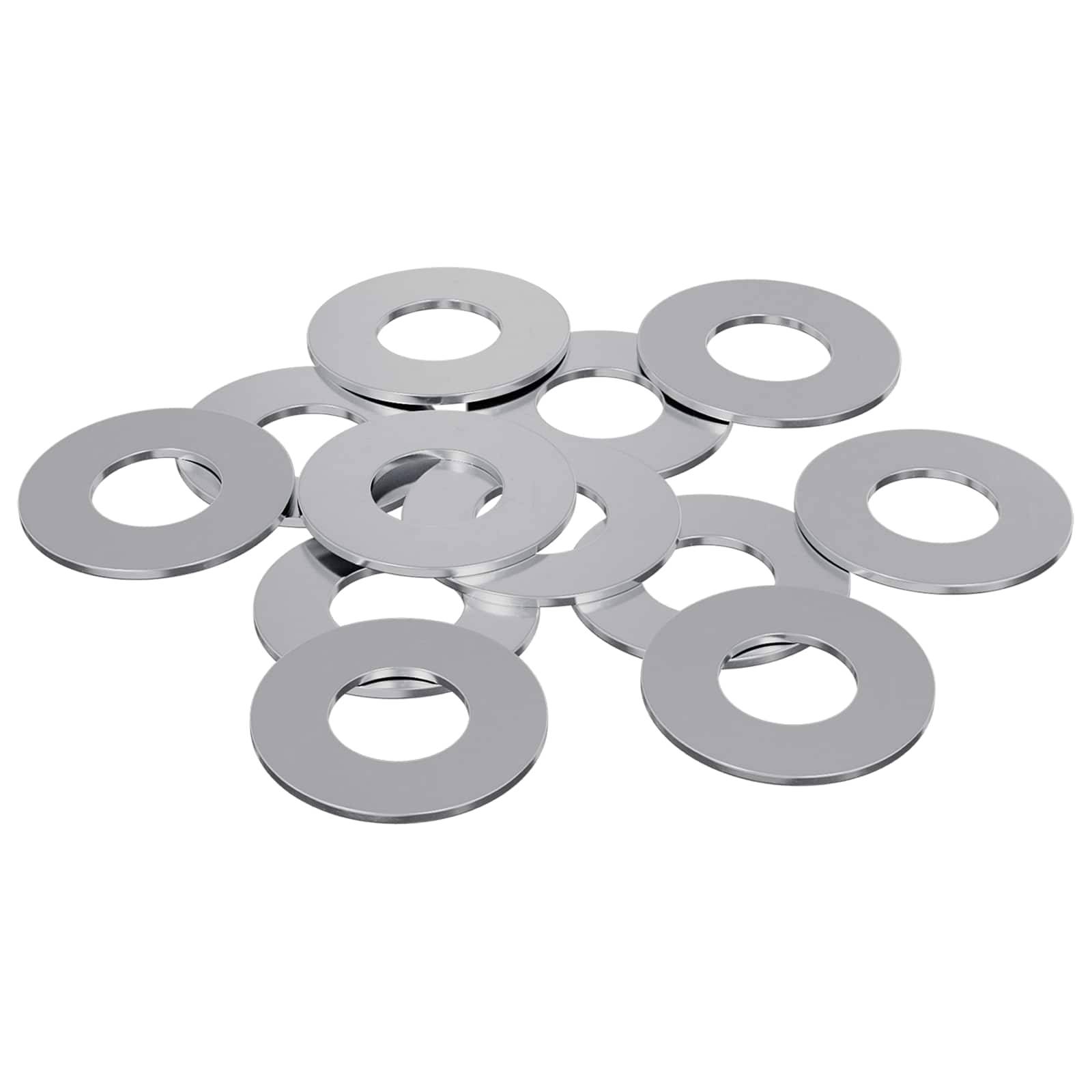 Ein Haufen silberner Metallunterlegscheiben, verstreut auf einer weißen Oberfläche, jede mit einem zentralen Loch, häufig bei mechanischen oder Konstruktionsaufgaben verwendet.