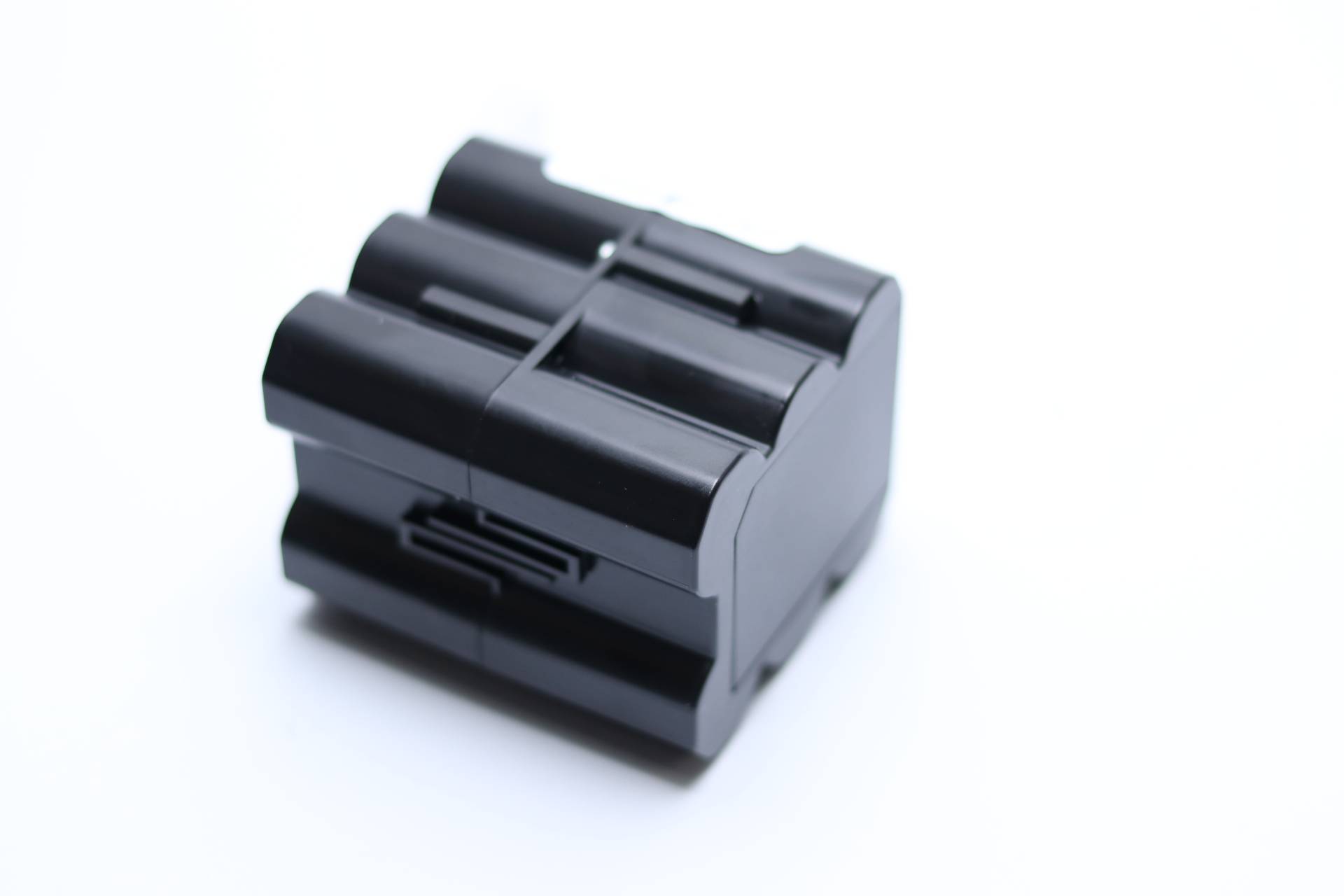 Ein schwarzer Kunststoffblock mit ineinandergreifenden Rillen aus schräger Perspektive, möglicherweise ein Verbinder oder Teil einer größeren Baugruppe.