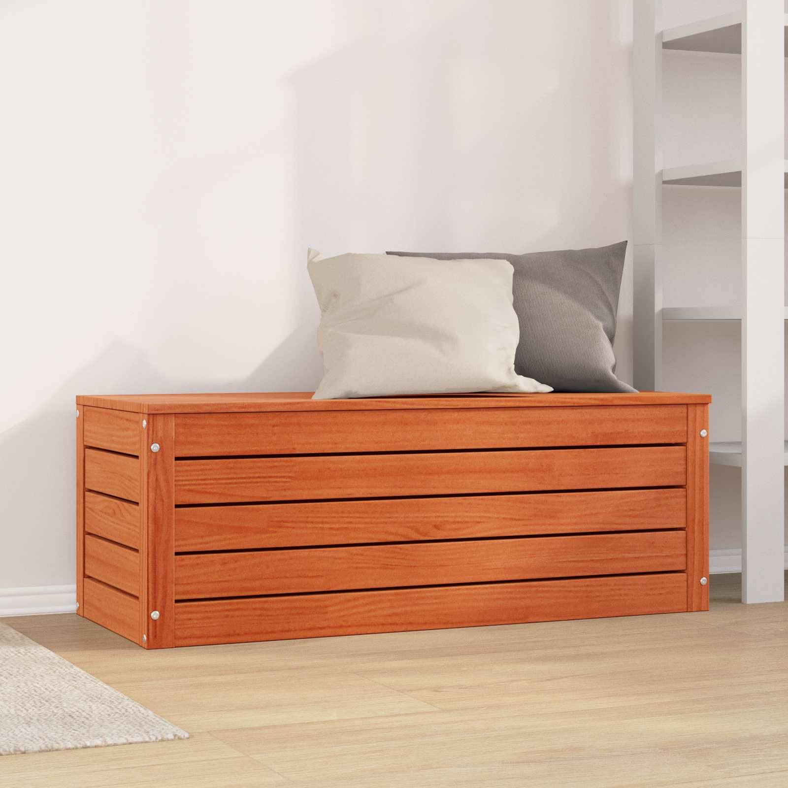 Eine Holzlagerkbank mit einer Lamellenkonstruktion, belegt mit zwei Kissen, ist in einem hellen Raum neben einem weißen Regalwürfel positioniert.