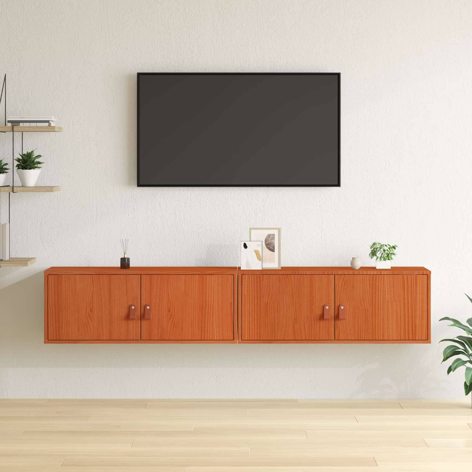 Ein modernes Wohnzimmer mit einem angebrachten Fernseher, Holzschränken und minimaler Dekoration, einschließlich einer kleinen Pflanze, einem gerahmten Bild und Regalen.