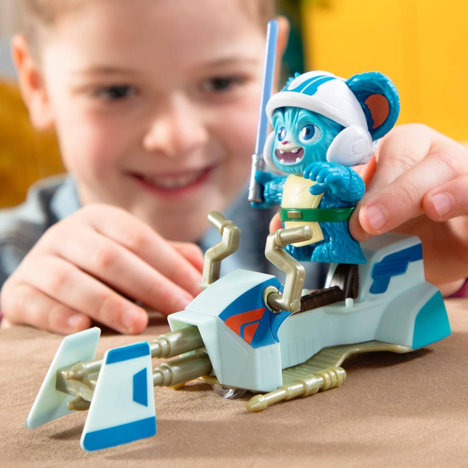 Ein Kind spielt glücklich mit einer blauen Alien-Figur, die auf einem Spielzeug-Schwebeplattform reitet, was Engagement und Kreativität im fantasievollen Spiel demonstriert.