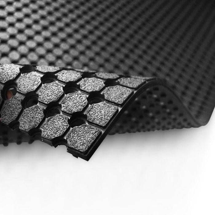 Nahaufnahme einer strukturierten, schwarzen Trainingsmatte mit einem Wabenmusters auf weißem Hintergrund, das Haltbarkeit und Designdetail zeigt.
