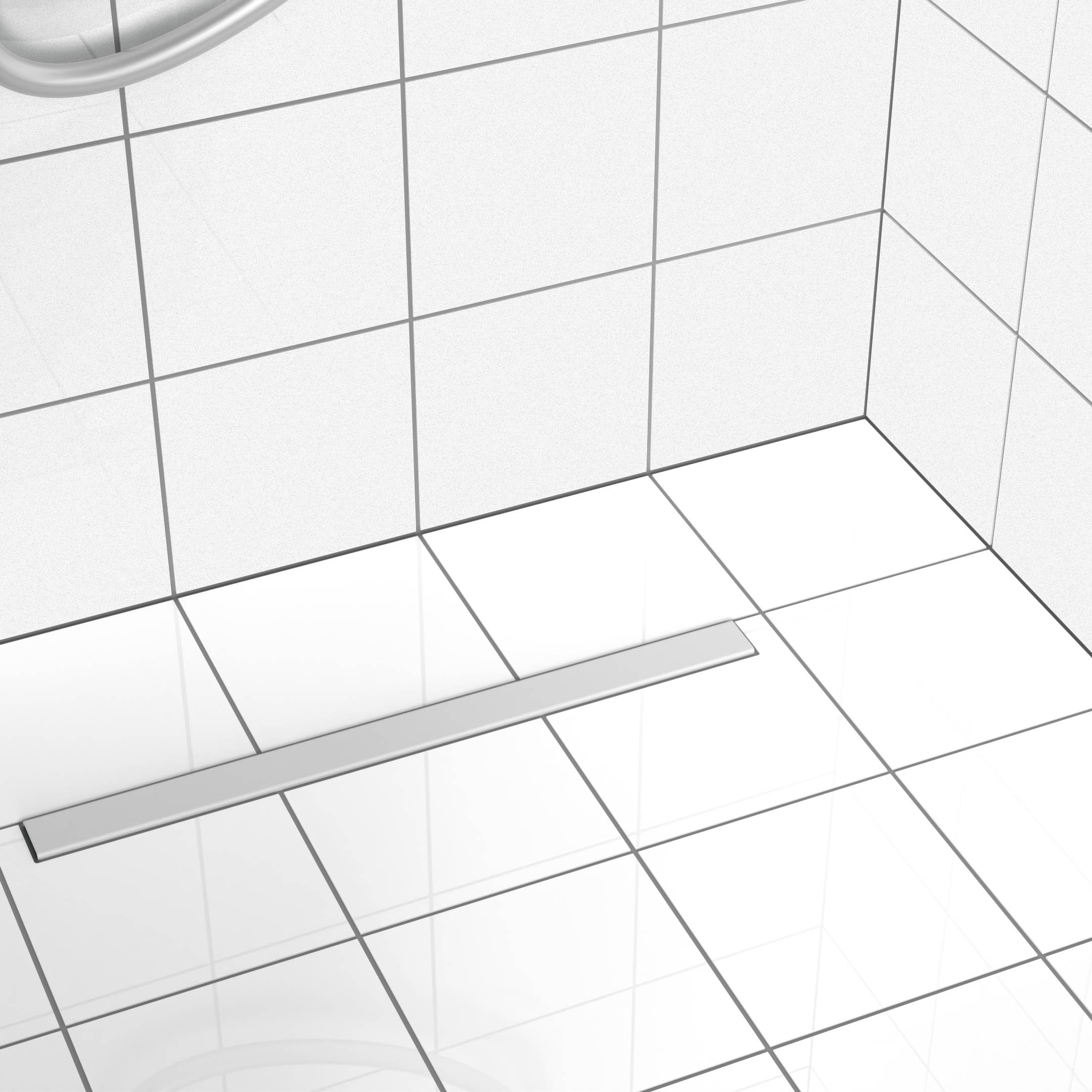 Ein weißer gefliester Badezimmerboden mit einem rechteckigen Metallablauf, der sich in einem Duschbereich befindet.