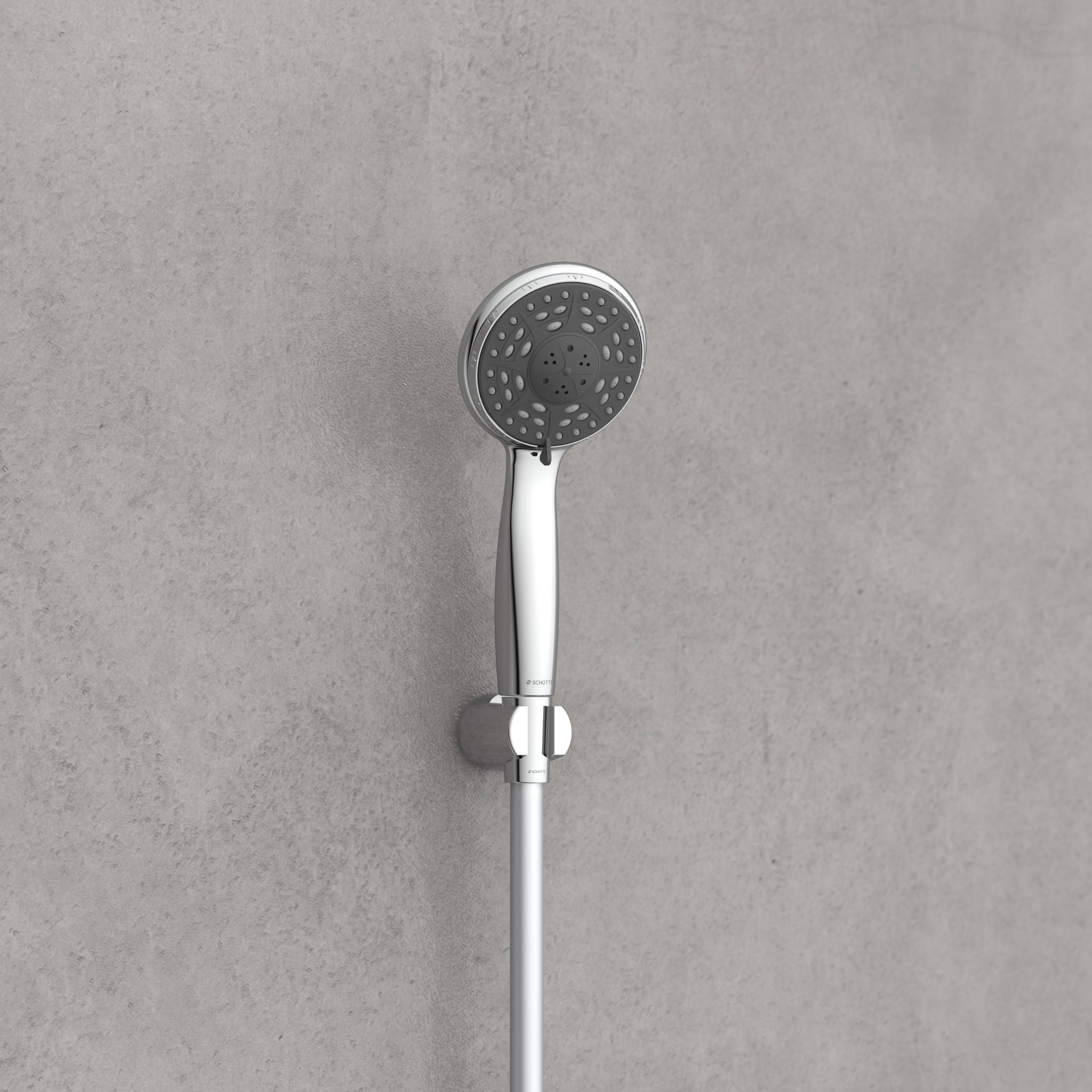 Ein moderner, verchromter tragbarer Duschkopf, der an einer grau gefliesten Badezimmerwand angebracht ist, mit einem flexiblen Schlauch, der ihn mit der Wandarmatur verbindet.