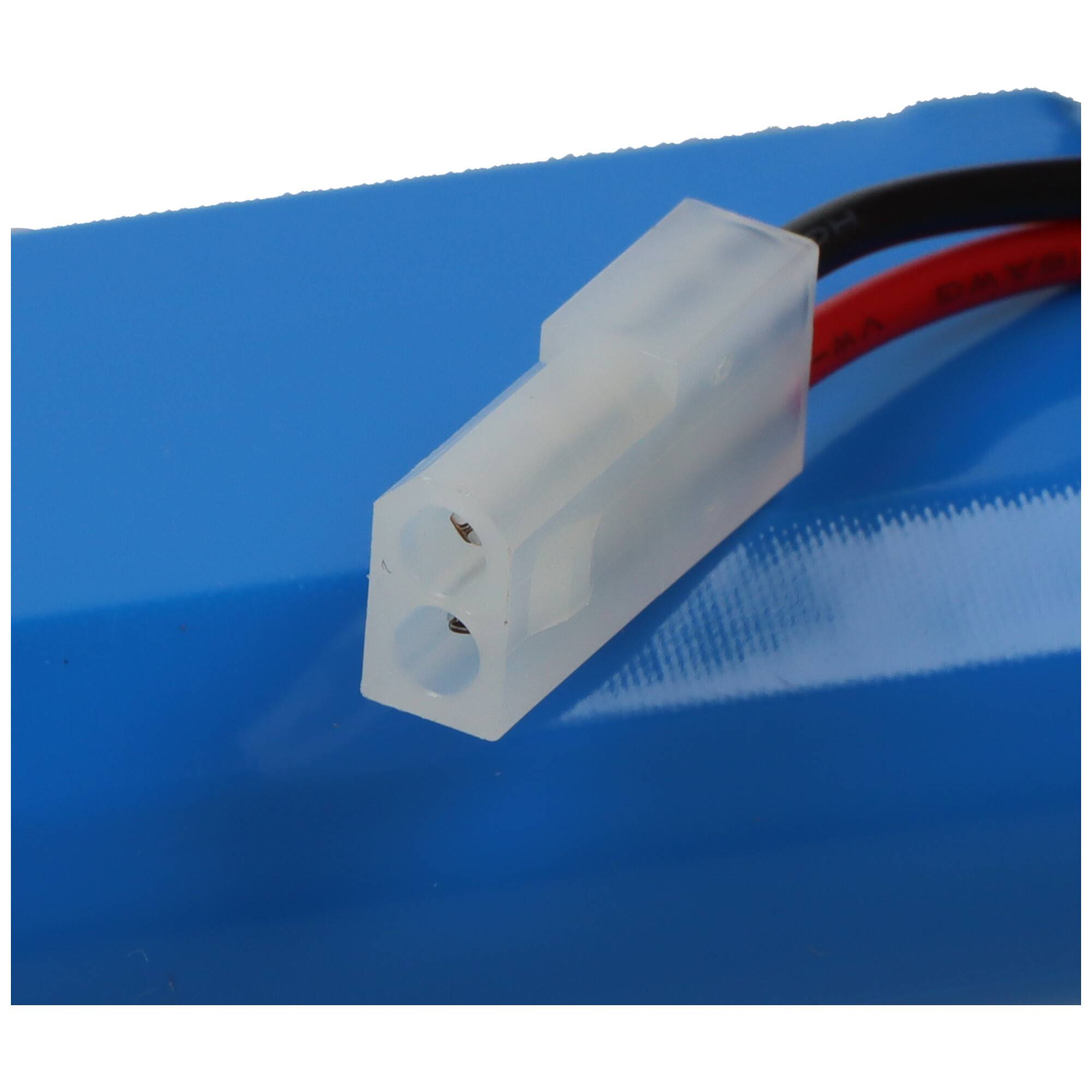 Eine Nahaufnahme eines weißen zweipoligen Elektroanschlusses, der an roten und schwarzen Drähten befestigt ist und auf einer blauen Oberfläche ruht.