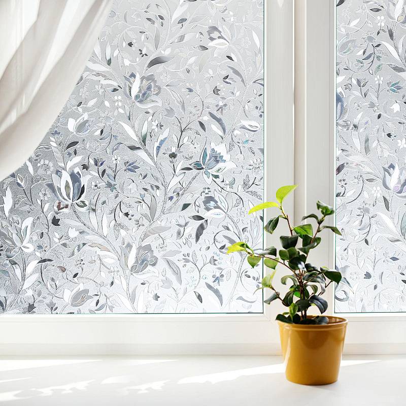 Ein sonnendurchflutetes Zimmer mit einer Topfpflanze auf einer Fensterbank. Das Fenster ist mit dekorativem Mattglas verziert, das ein Blumenmuster aufweist.