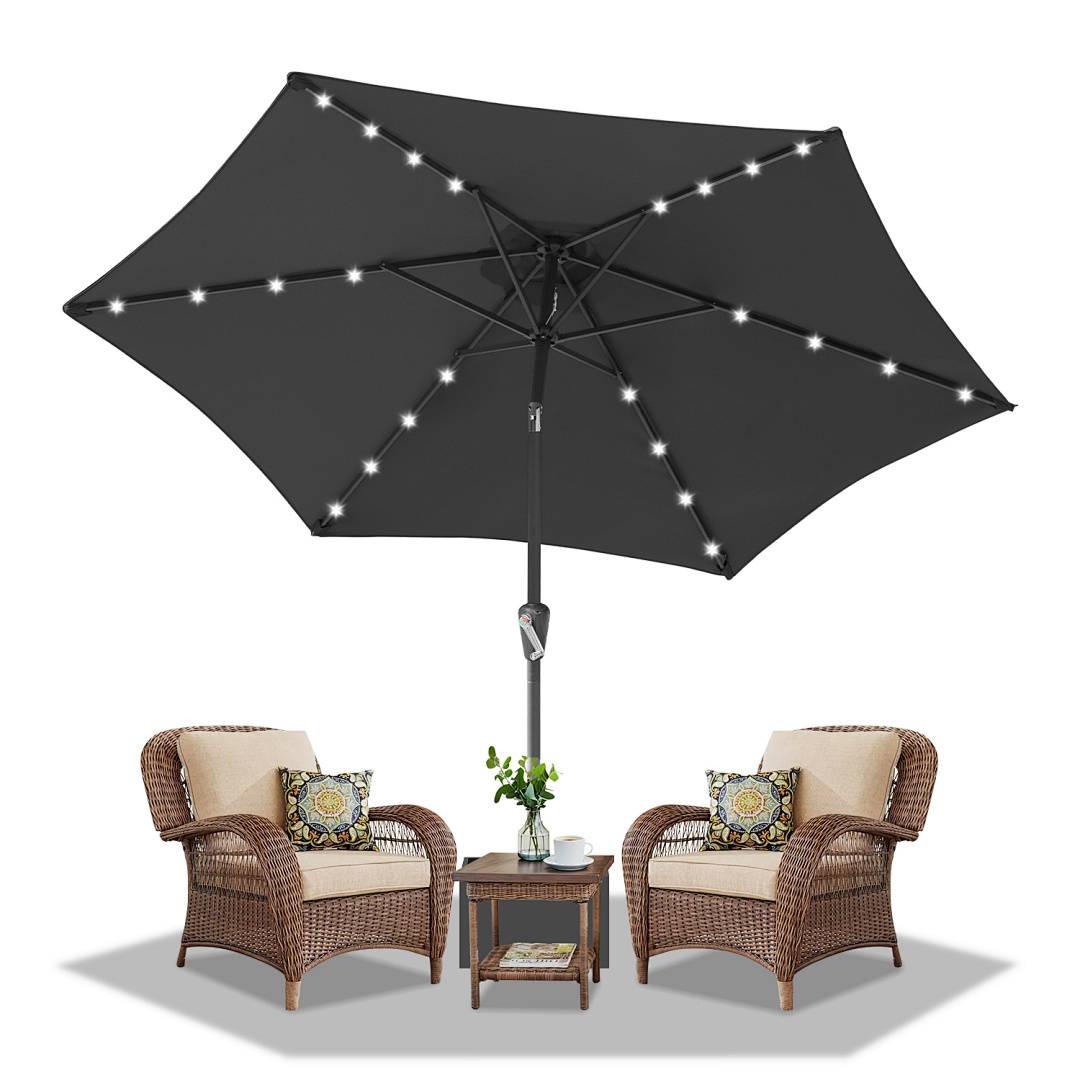 Gartenmöbelset mit zwei Korbstühlen mit Kissen, einem kleinen Tisch mit einer Vase und einem großen Schirm mit Lichterkette.