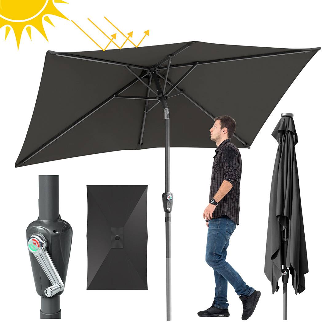 Ein Mann steht unter einem schwarzen Terrassenschirm, der die Sonne teilweise blockiert, und zeigt dessen verstellbare Neigungsfunktion zum Schutz vor Schatten.