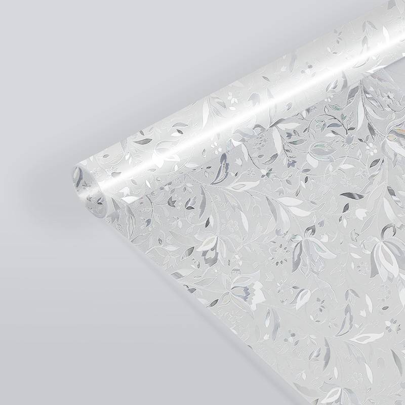 Rolle mit blumenmusterter Tapete in Weiß- und Grautönen, auf hellgrauem Hintergrund ausgerollt.