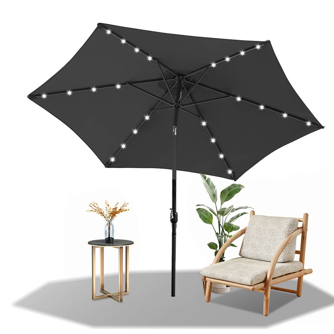 Ein schwarzer Terrassenschirm mit LED-Lichtern steht offen. Daneben ein Holzstuhl mit beigen Kissen und ein kleiner runder Tisch mit einer Vase.