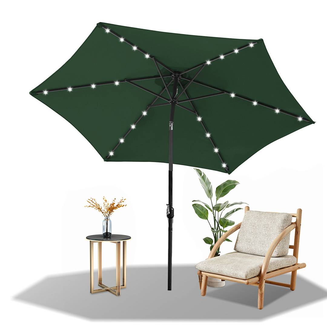 Ein grüner Terrassenschirm mit Lichterketten steht neben einem Holzstuhl und einem kleinen Tisch mit einer Blumenvase, neben einer Topfpflanze.