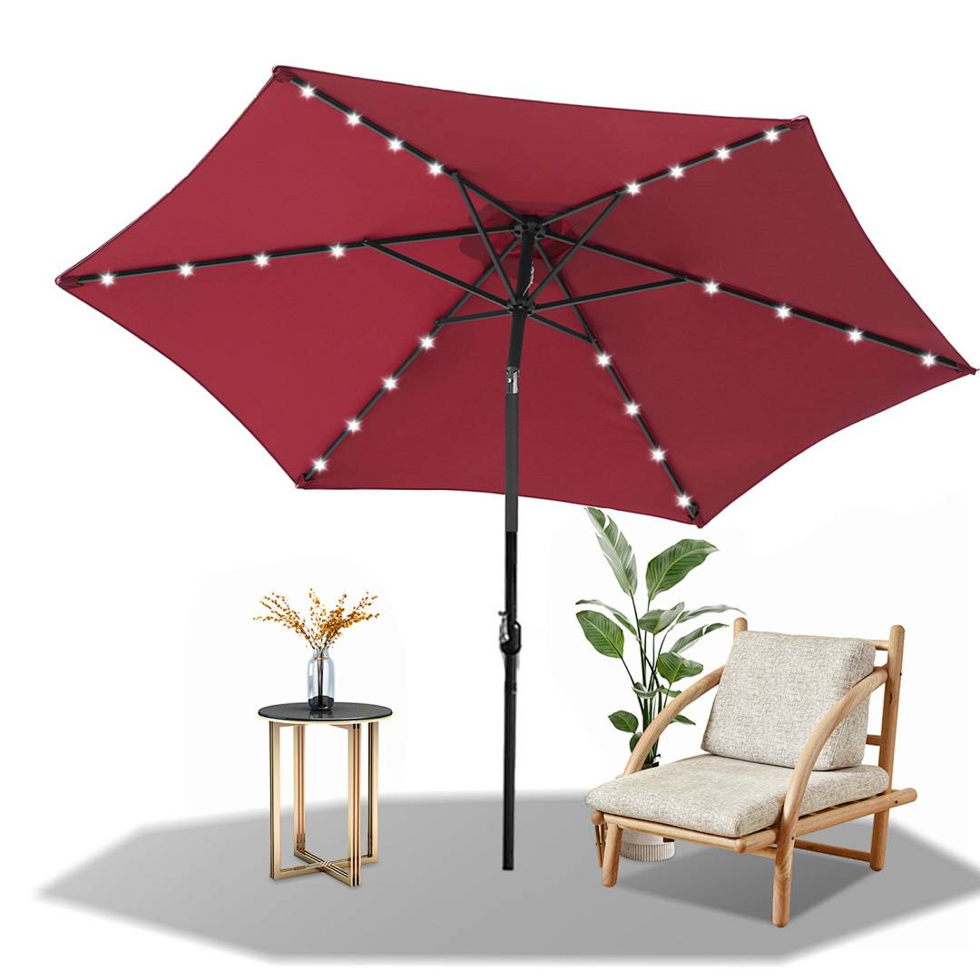 Ein roter Terrassenschirm mit LED-Leuchten ist über einem Holz-Liegestuhl und einem kleinen Beistelltisch mit einer Topfpflanze aufgespannt und schafft eine gemütliche Außenbereichsausstattung.