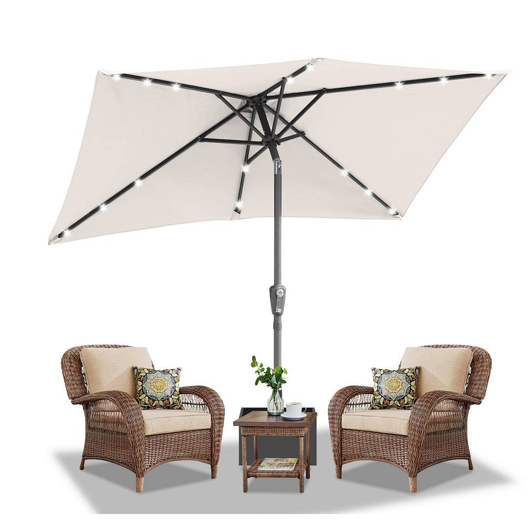 Eine Terrassenkonfiguration mit zwei Korbstühlen, Kissen und einem zentralen Tisch unter einem großen weißen Schirm mit Lichterketten, die einen gemütlichen Außenbereich schaffen.
