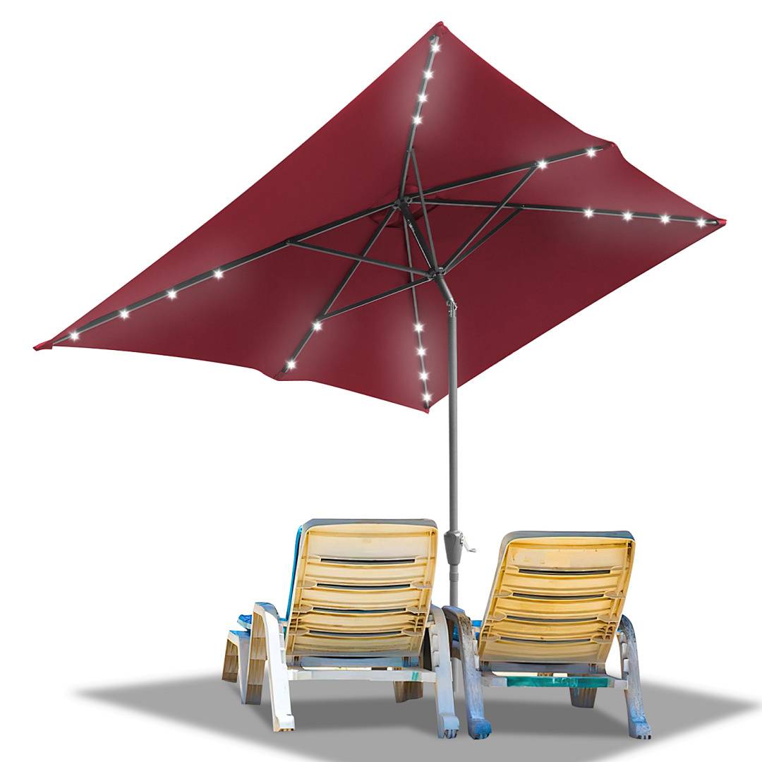 Zwei gelbe Liegestühle unter einem großen roten Regenschirm mit Lichterketten.