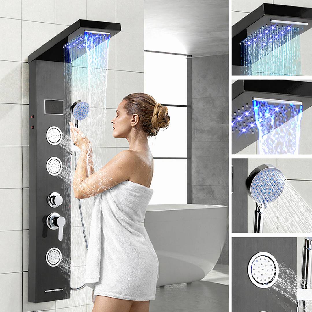 Eine Frau duscht unter einem modernen Duschpaneel mit mehreren Düsen und blauen LED-Leuchten in einem hellen Badezimmer mit einer Badewanne.