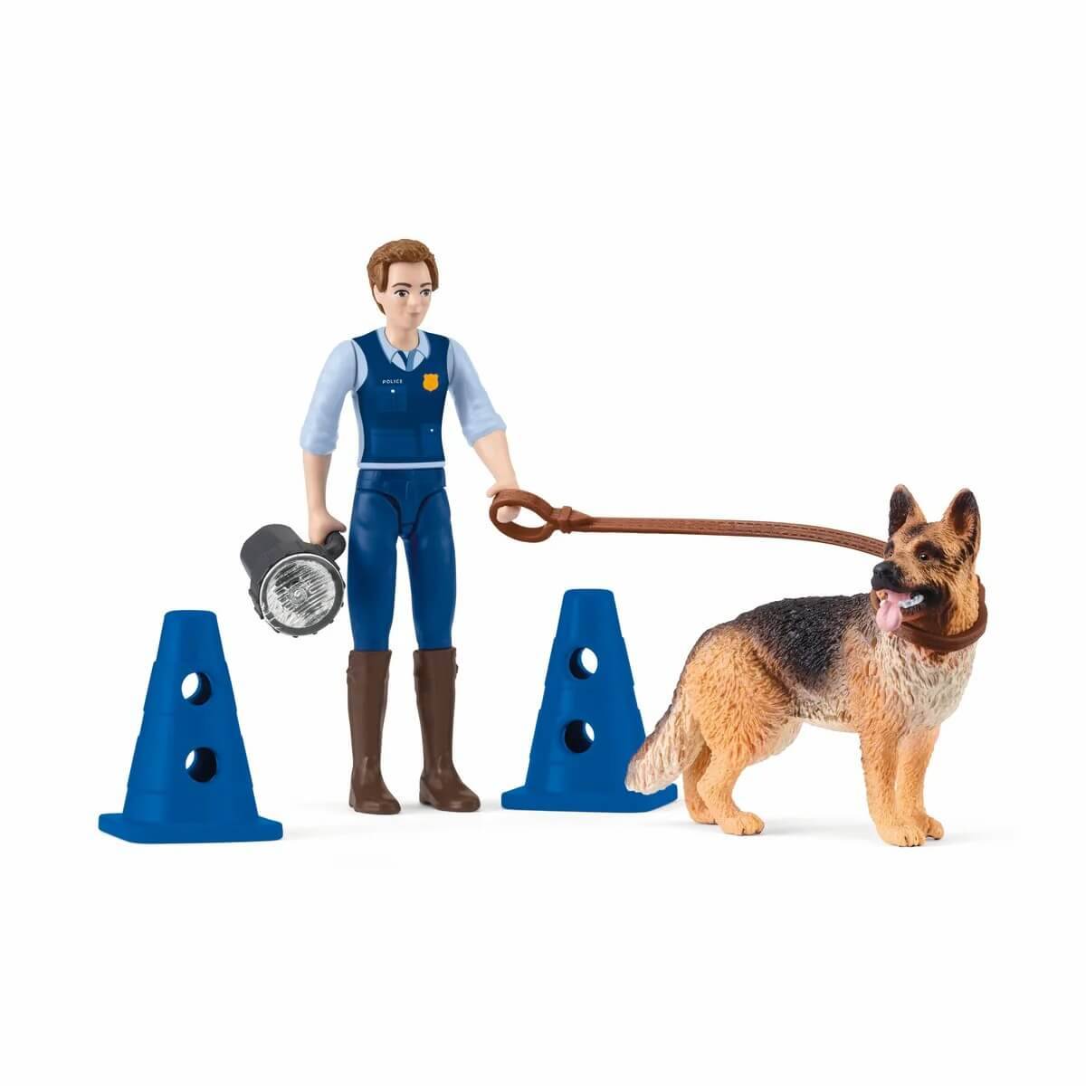 Eine Spielzeugfigur eines Polizisten, der einen Deutschen Schäferhund an der Leine hält, mit zwei blauen Kegeln.