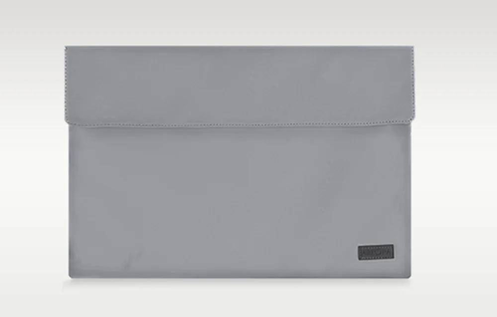 Eine schlanke, graue rechteckige Laptop-Schutzhülle mit einem dezenten Logo in der unteren rechten Ecke, vor einem einfarbigen Hintergrund.