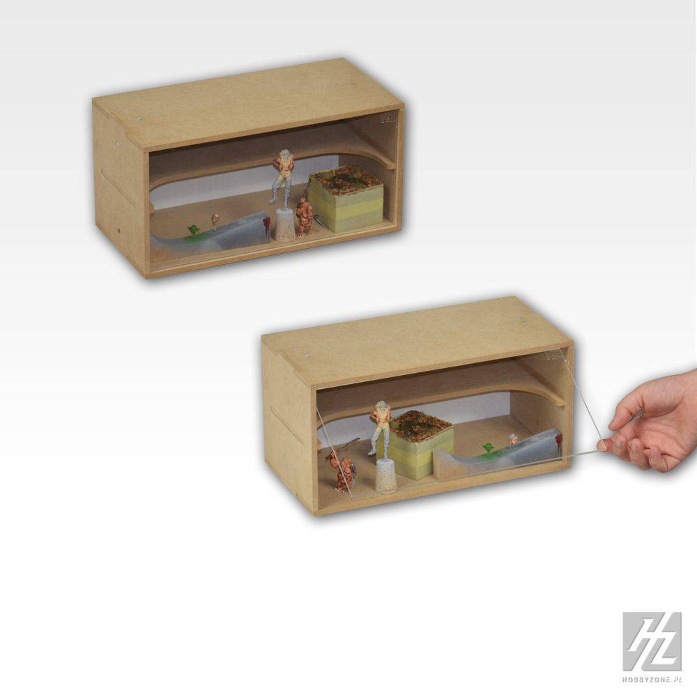 Eine Hand hält eine Schnur, die mit einem Diorama in einer Pappschachtel verbunden ist, das eine kleine Szene mit einer Figur und verschiedenen Miniaturgegenständen darstellt.