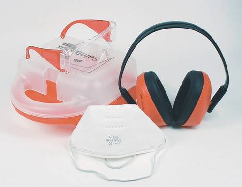 „Gehörschutz und eine Maske auf einem Tisch, mit roten Ohrenschützern und einer weißen Schutzmaske, die Schutzausrüstung für Lärm- und Atemwegsgefährdungen symbolisieren.