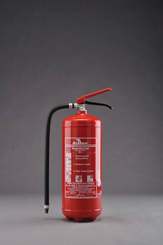 Ein roter Feuerlöscher mit Schlauch und Düse vor grauem Hintergrund. Etiketten mit Anweisungen sind auf seiner Oberfläche sichtbar.