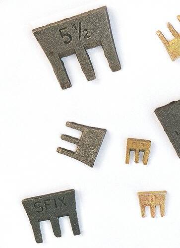 Assortierte kleine schwarze und goldene Metallstücke mit Zahlen und Buchstaben, einschließlich 