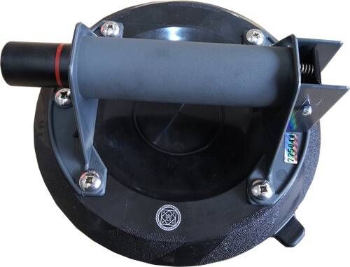 Eine Nahaufnahme eines Saugnapfs mit grauem Griff und schwarzer Basis, mit vier Metallschrauben, verwendet zum Anheben glatter Oberflächen.